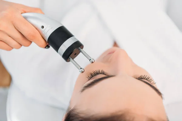 Atractiva mujer recibiendo terapia de microcorriente facial en el salón de spa - foto de stock