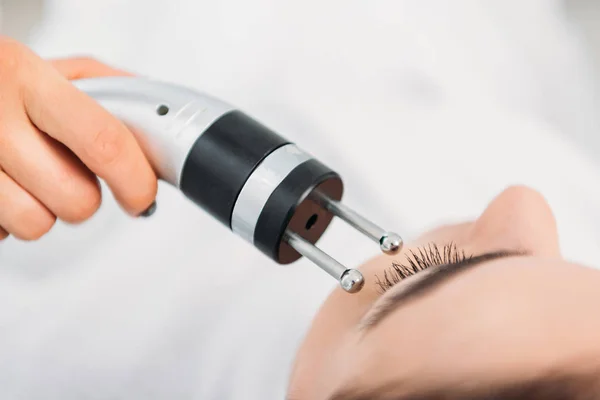 Tiro recortado de la mujer recibiendo terapia de microcorriente facial en el salón de spa - foto de stock