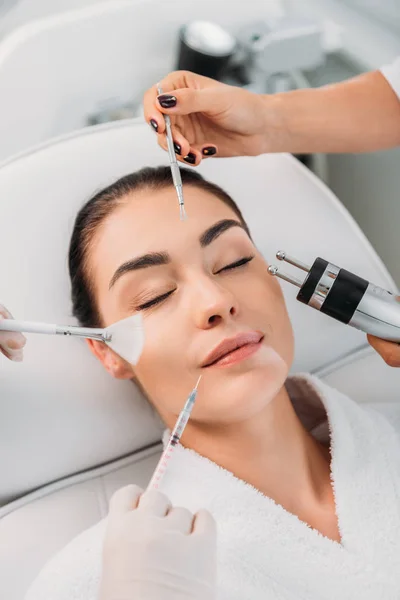 Woman with various facial treatment equipment around in spa center — Stock Photo