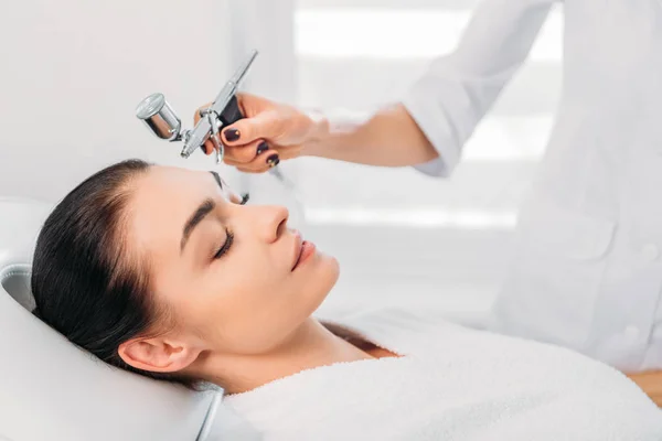 Attractive woman receiving facial treatment in spa center — Stock Photo