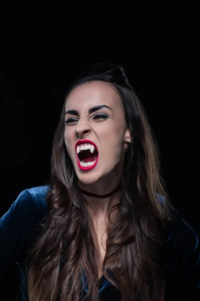 Красивая женщина, показывающая вампирские зубы, изолированные на черном — стоковое фото