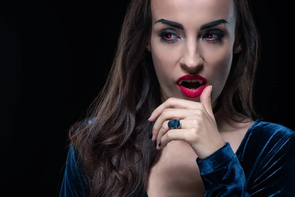 Grim vampire touching her lips isolated on black — Stock Photo