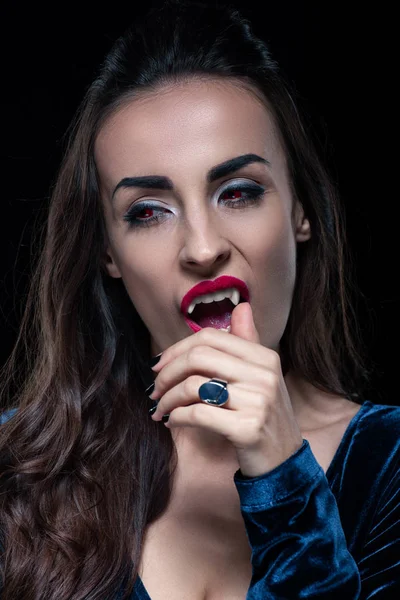 Sexy vampiro tocando su colmillo aislado en negro - foto de stock