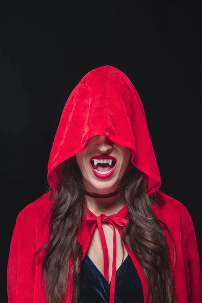 Vampire woman in red cloak showing her fangs isolated on black — Stock Photo