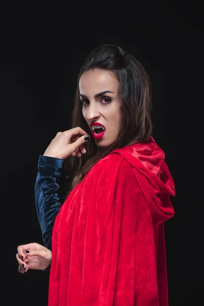 Жахлива вампірська жінка в червоному плащі, що показує свої зуби ізольовані на чорному — стокове фото
