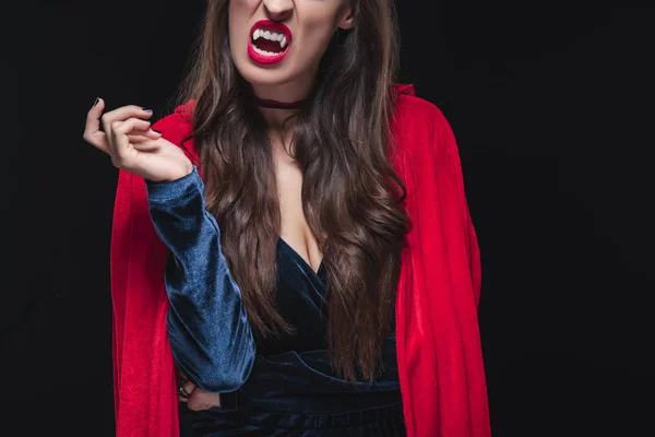 Vue recadrée de vampire femme en manteau rouge montrant ses crocs isolés sur noir — Photo de stock