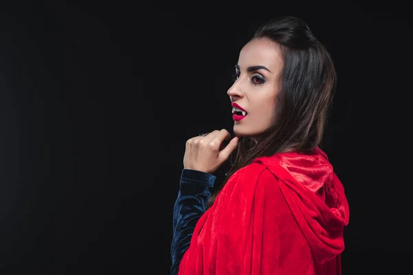 Красива вампірська жінка в червоному плащі ізольована на чорному — стокове фото