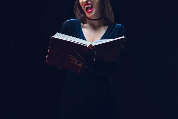 Обрізаний вид вампіра жінка тримає чарівну книгу ізольовано на чорному — стокове фото