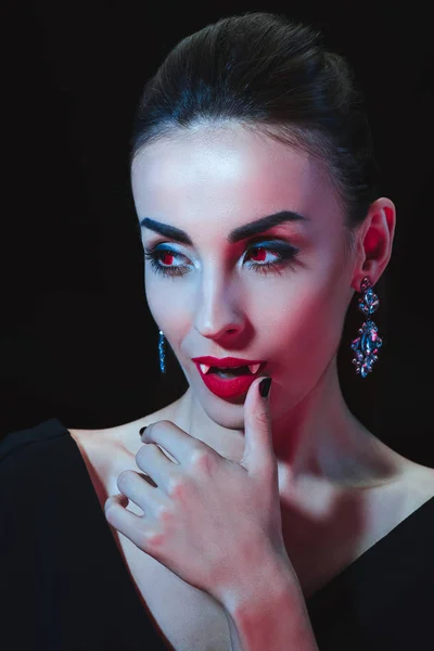 Привабливий вампір торкається її губ ізольовано на чорному — стокове фото