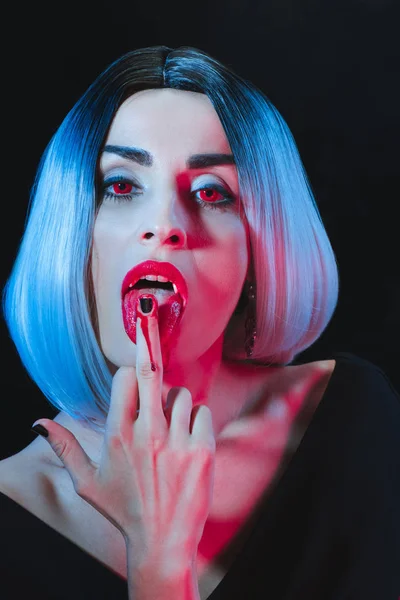 Сексуальний вампір лиже її середній палець ізольовано на чорному — стокове фото