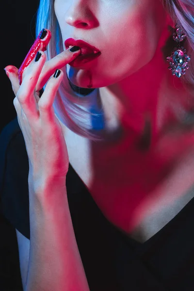 Cropped view of vampire licking her fingers on dark background with smoke — Stock Photo