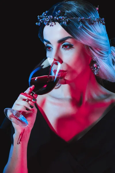 Beautiful vampire drinking blood from wineglass isolated on black — Stock Photo