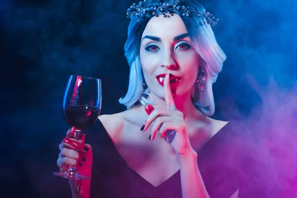 Vampir hält Weinglas mit Blut und zeigt Schweigesymbol auf Dunkelheit mit Rauch — Stockfoto