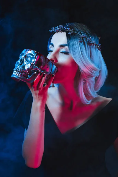 Mujer vampiro bebiendo sangre del cráneo en la oscuridad con humo - foto de stock