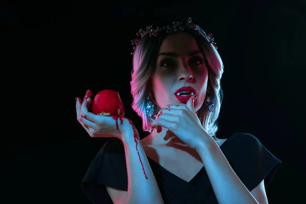 Готическая женщина с красным яблоком, изолированным на черном — стоковое фото