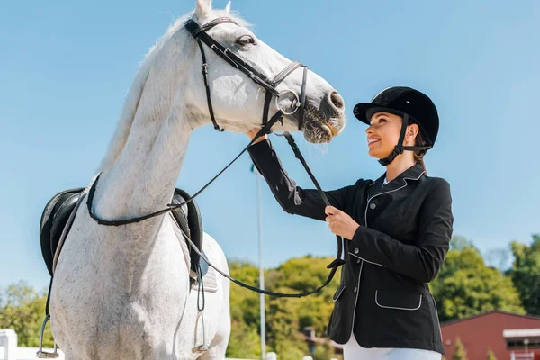 Atraente fêmea equestre palming cavalo no clube de cavalos — Fotografia de Stock