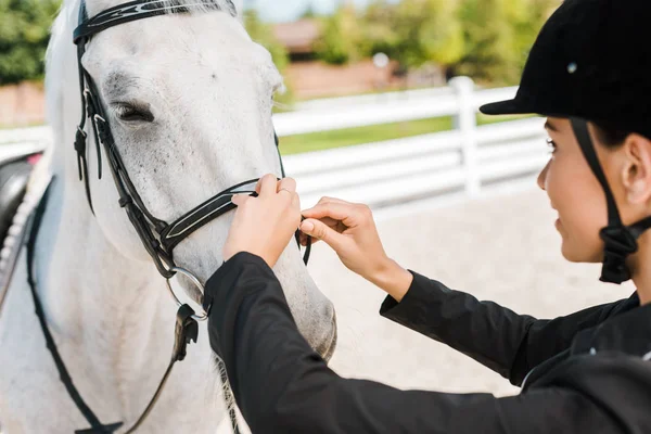Side view of female equestrian fixing horse halter at horse club — Stock Photo