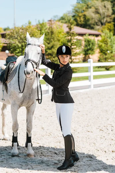 Привлекательная женщина конница фиксирует лошадиный холтер и смотрит в сторону конного клуба — стоковое фото