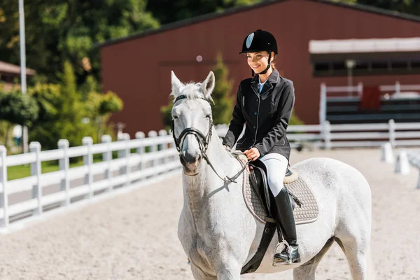 Attractive smiling female equestrian riding horse at horse club — Stock Photo