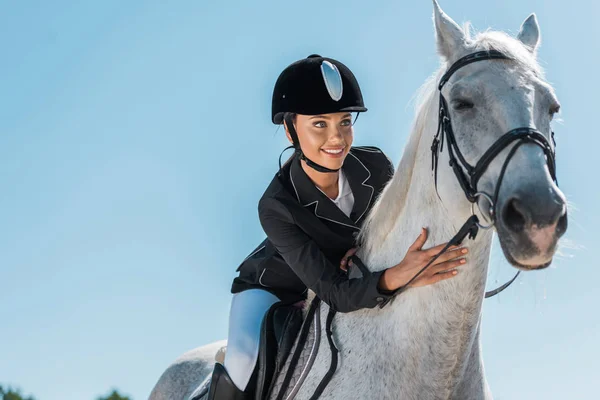 Attractive female equestrian riding beautiful white horse at horse club — Stock Photo