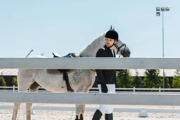 Красивый мужчина конный ходьба с лошадью рядом с забором в конном клубе — стоковое фото