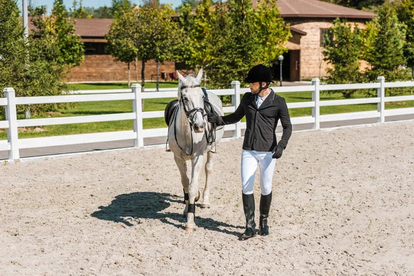 Handsome male equestrian walking near horse at ranch — Stock Photo