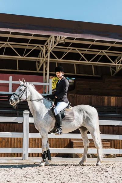 Vista lateral do belo masculino jockey equitação cavalo no clube de cavalos — Fotografia de Stock