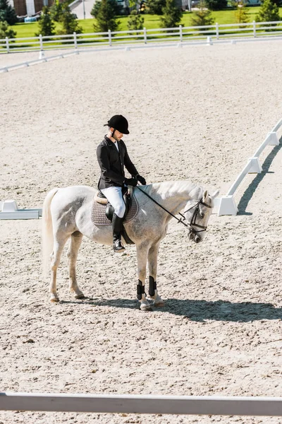 Vista lateral do jóquei masculino sentado a cavalo no rancho — Fotografia de Stock