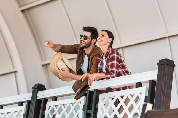Smiling man pointing on something to woman from tribune at ranch stadium — Stock Photo