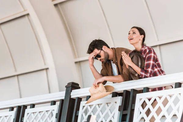 Расстроенный мужчина и молящаяся женщина смотрят скачки на стадионе ранчо — стоковое фото