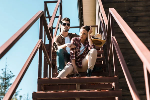 Ковбой и ковбойша в повседневной одежде сидят на металлической лестнице на ранчо — стоковое фото