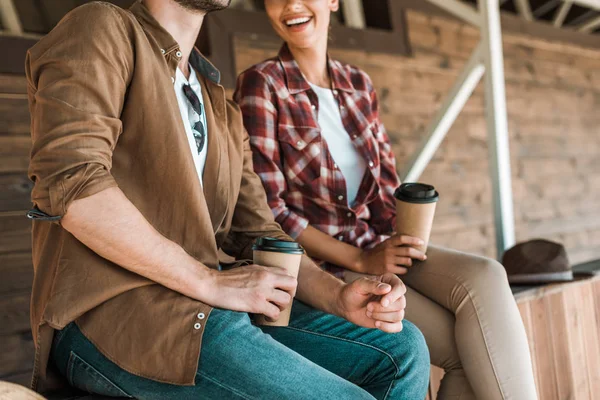 Cropped image of cowboy and cowgirl sitting with disposable coffee cups at ranch — Stock Photo