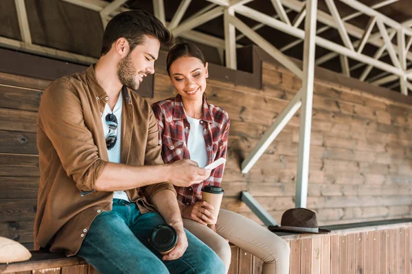 Smiling man and woman sitting and looking at smartphone at ranch — Stock Photo