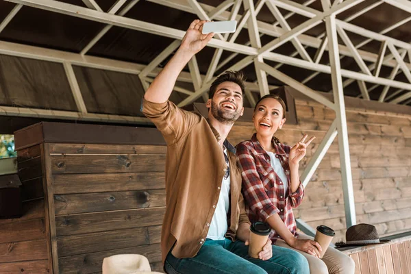 Smiling cowboy and cowgirl taking selfie with smartphone at ranch — Stock Photo