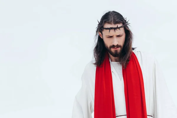 Jesus in robe, red sash and crown of thorns looking down against light sky — Stock Photo