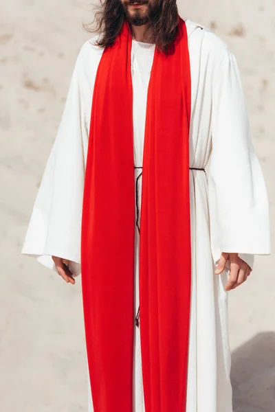 Image recadrée de Jésus en robe et ceinture rouge debout dans le désert — Photo de stock