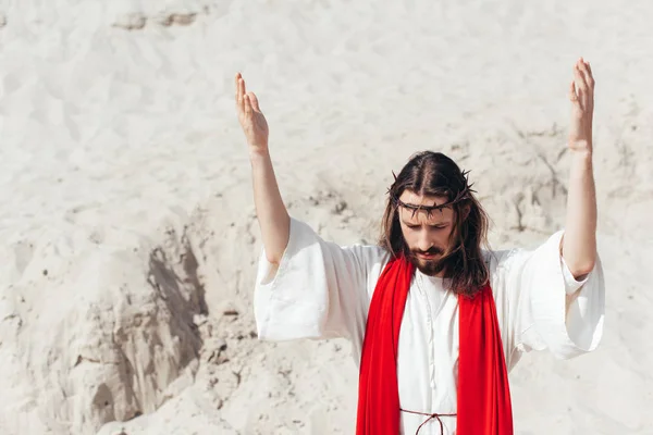 Jesus standing with raised hands and praying in desert — Stock Photo