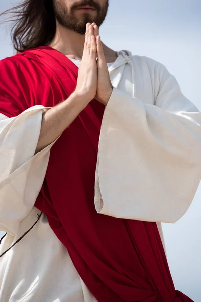 Cropped image of Jesus in robe and red sash praying outdoors — Stock Photo