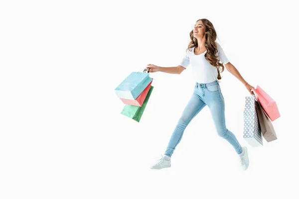 Atractiva chica feliz saltando con bolsas de compras, aislado en blanco - foto de stock