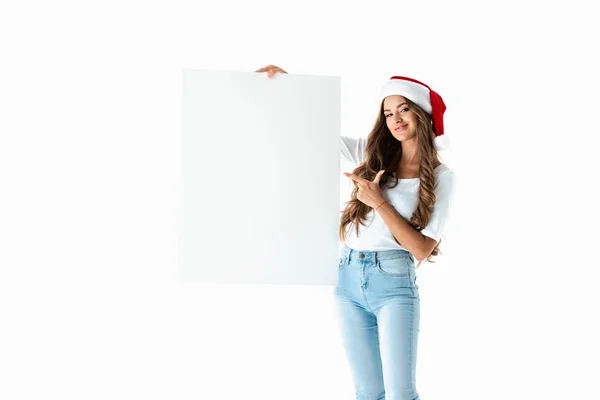 Sonriente chica en santa hat apuntando en blanco vacío tablero, aislado en blanco - foto de stock