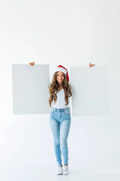 Schöne junge Frau mit Weihnachtsmannmütze und leeren Brettern, isoliert auf weiß — Stockfoto