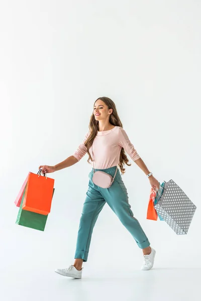 Schöne glückliche Frau, die mit Einkaufstaschen geht, isoliert auf weiß — Stockfoto