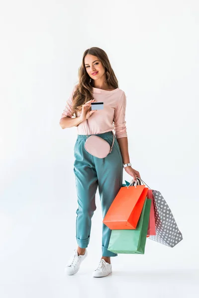 Chica feliz sosteniendo la tarjeta de crédito y bolsas de la compra, aislado en blanco - foto de stock