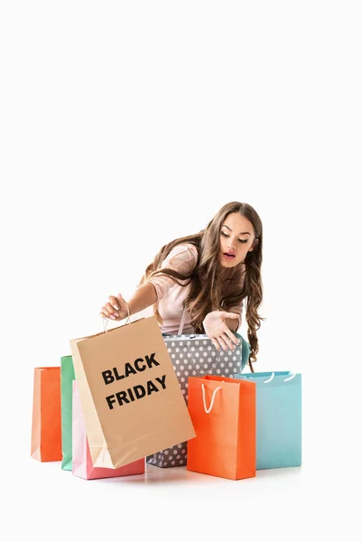 Chica sorprendida sosteniendo bolsas de compras para el viernes negro, aislado en blanco - foto de stock