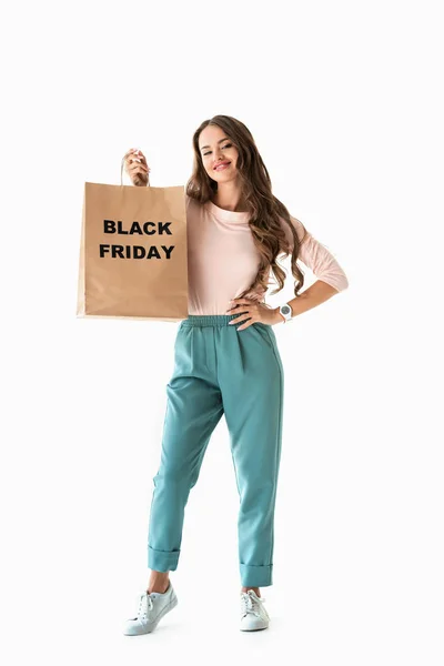 Smiling girl showing shopping bag with black friday sign, isolated on white — Stock Photo