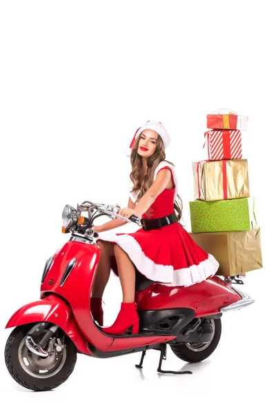 Menina morena feliz no traje de santa dirigindo scooter vermelho com presentes, isolado no branco — Fotografia de Stock