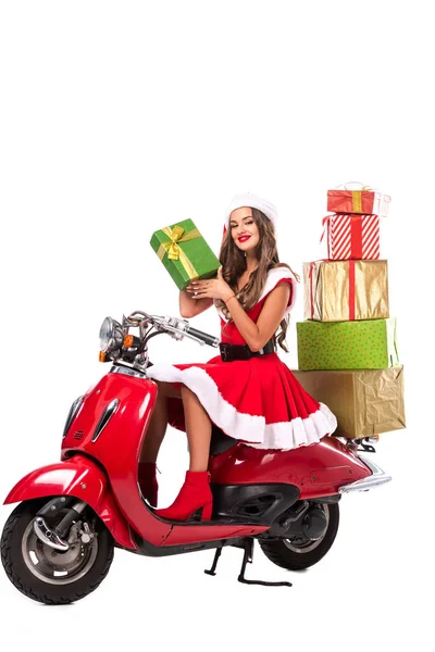 Attrayant fille en costume de Père Noël conduite scooter rouge avec des boîtes-cadeaux, isolé sur blanc — Photo de stock