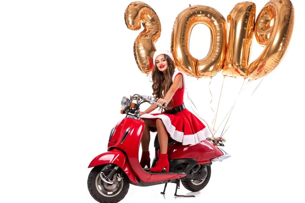 Happy girl in santa costume driving red scooter with 2019 new year golden balloons, isolated on white — Stock Photo