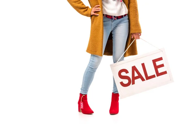 Vista cortada da menina no outono roupa segurando placa com sinal de venda, isolado no branco — Fotografia de Stock