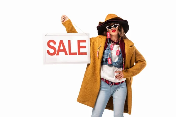 Stylish girl in trendy autumn outfit with sale tags holding board with sale sign, isolated on white — Stock Photo